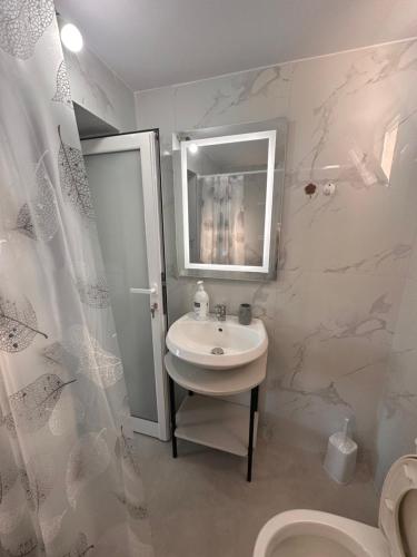 ein Badezimmer mit einem Waschbecken, einem Spiegel und einem WC in der Unterkunft Andi's GuestHouse in Sarandë