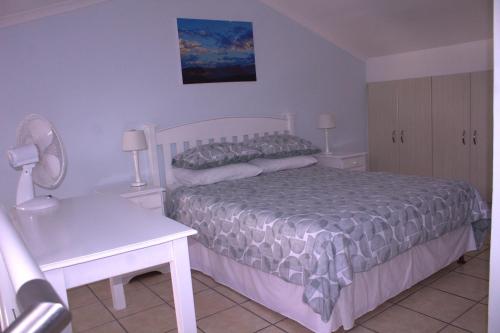 a bedroom with a bed and a table and a desk at South Peninsula Beach Apartment in Cape Town