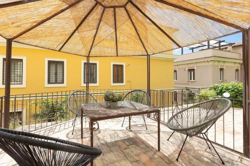 eine Terrasse mit einem Tisch, Stühlen und einem Sonnenschirm in der Unterkunft Appartamento San Pietro-Vaticano in Rom