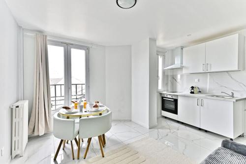 une cuisine blanche avec une table et des chaises blanches dans l'établissement Appartement Spacieux dans la banlieue parisienne, à Gagny