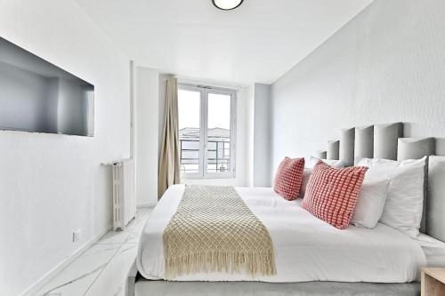 - une chambre blanche avec un grand lit et des oreillers rouges dans l'établissement Appartement Spacieux dans la banlieue parisienne, à Gagny