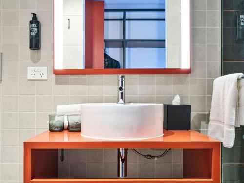 ibis Styles Melbourne Airport في ملبورن: حمام مع حوض ومرآة