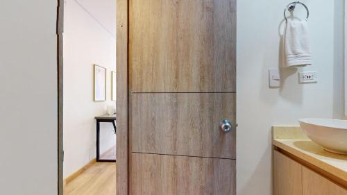 a bathroom with a wooden door next to a sink at gA Cabrera 85-12 Nuevo Loft en Zona T in Bogotá