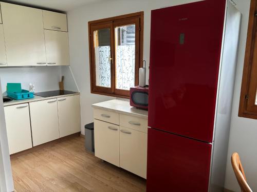 a kitchen with a red refrigerator and white cabinets at Apartma Zala-Terme Čatež in Mostec