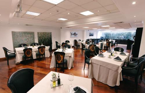 una sala da pranzo con tavoli e sedie bianchi di BTH Hotel Lima Golf a Lima