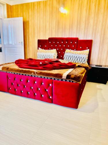 un lit rouge avec une tête de lit rouge dans une chambre dans l'établissement Rahmat manzul, à Nathia Gali
