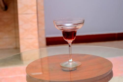 un bicchiere di vino seduto sopra un tavolo di EQUATOR GATES HOTEL Bulega a Bulenga