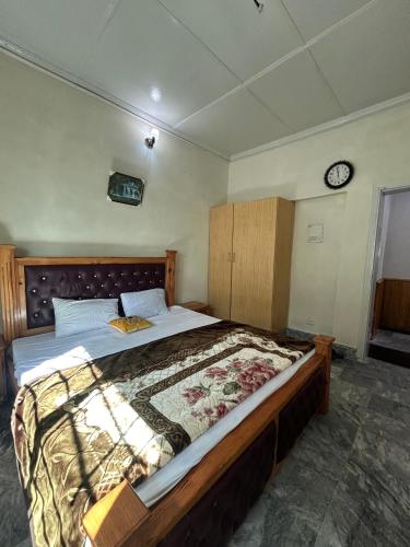 - une chambre avec un grand lit et une horloge murale dans l'établissement Rahmat manzul, à Nathia Gali