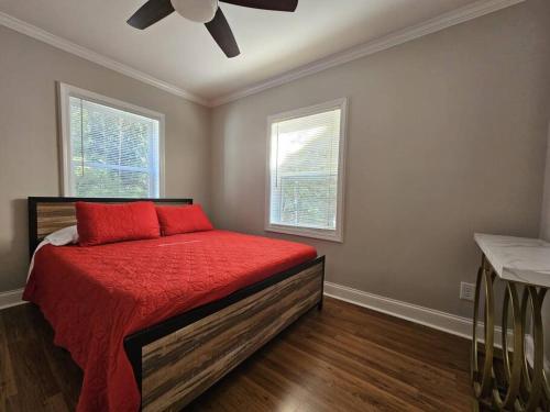 - une chambre avec un lit doté d'une couette rouge et 2 fenêtres dans l'établissement Gorgeous 2BR home with Private Backyard, à Atlanta