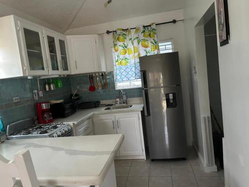 La cuisine est équipée de placards blancs et d'un réfrigérateur en acier inoxydable. dans l'établissement Beautiful Vacation Home, à Ocho Rios