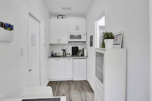 a white kitchen with white cabinets and a table at Cozy Studio Apartment in Miami