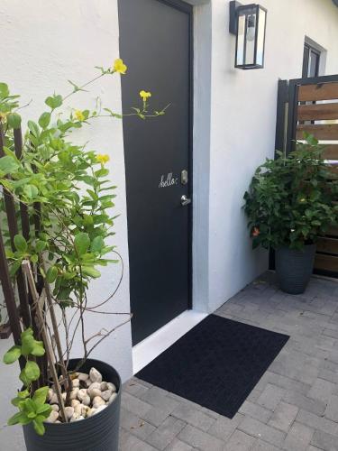 a black door with a flower on it next to plants at Cozy Studio Apartment in Miami