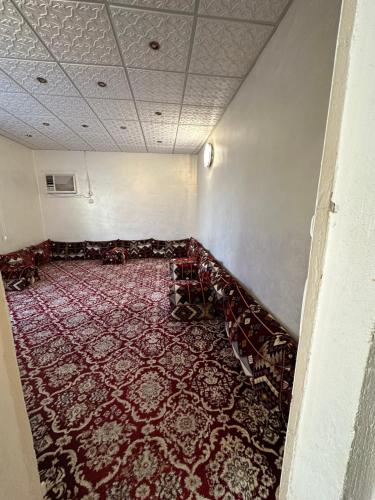 an empty room with a red rug on the floor at ملحق in Taif