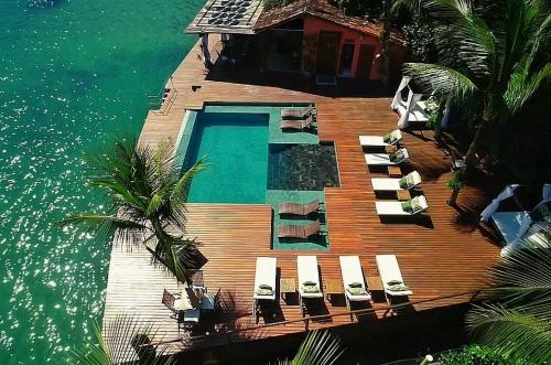 a wooden deck with chairs and a swimming pool in the water at Pousada e Mergulho Jamanta in Angra dos Reis