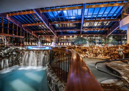 - une grande piscine intérieure avec une cascade dans un bâtiment dans l'établissement Luxe 10 guest Ski Cabin Pools/Golf/Tennis/Gym/Hike, à Vernon Township