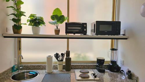 a counter with a microwave and a computer on a shelf at Apartamento con terraza privada junto al Bulevar del Rio in Cali