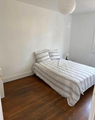 um quarto branco com uma cama com um cobertor listrado em Chambre Bron em Bron