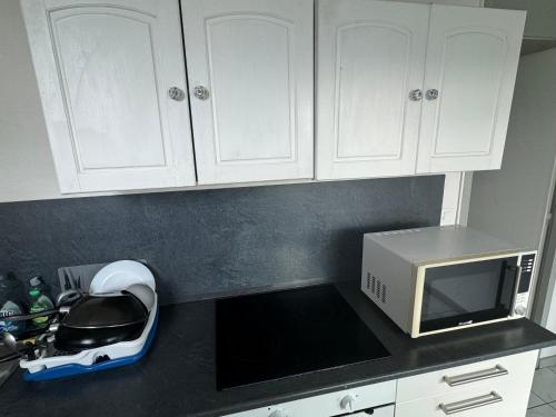 uma cozinha com armários brancos e um micro-ondas branco em Chambre Bron em Bron