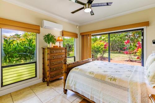 a bedroom with a bed and large windows at Hale Imaka in Kipu