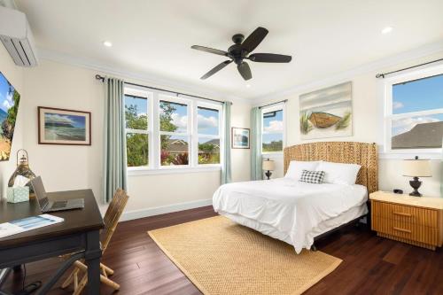 a bedroom with a bed and a desk and windows at Kolepa Kai in Koloa