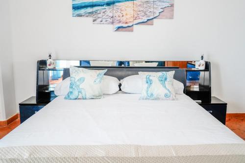a bedroom with a white bed with blue and white pillows at Appartamento Marirò in Racale