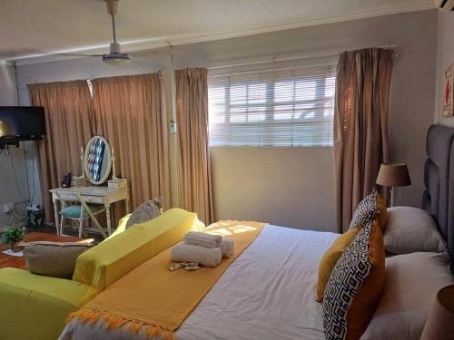 um quarto com uma cama grande e um sofá amarelo em Devine Stay- Pmb em Pietermaritzburg
