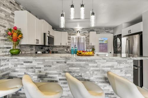 a kitchen with white cabinets and a counter with chairs at Malia Makai - D - Dolphin in Koloa