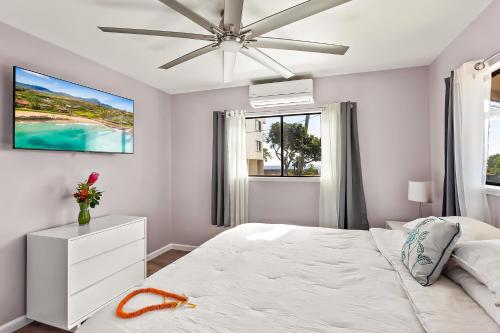 a white bedroom with a bed and a ceiling fan at Malia Makai - D - Dolphin in Koloa