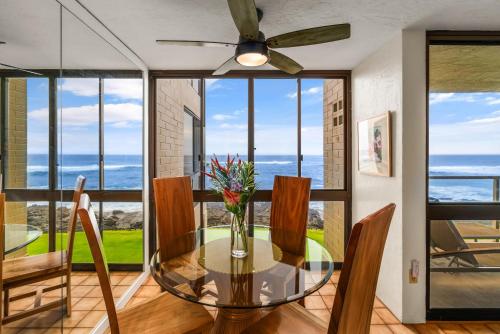 a dining room with a glass table with a view of the ocean at Kuhio Shores 215 in Koloa