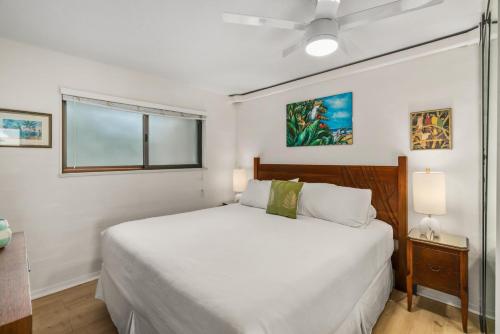 a white bedroom with a bed and a window at Kuhio Shores 215 in Koloa
