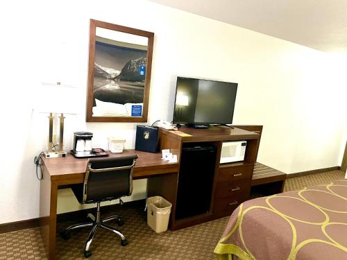 a hotel room with a desk with a television and a bed at Super 8 by Wyndham Hinton in Hinton