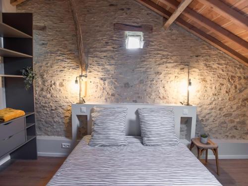 um quarto com uma cama numa parede de pedra em La grande Grange em Loubejac