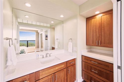 a bathroom with a sink and a large mirror at Poipu Shores 101A in Koloa