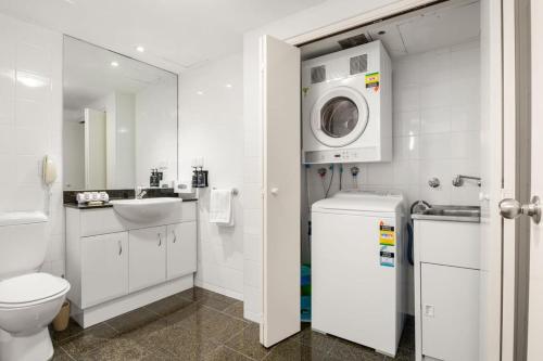 a white bathroom with a toilet and a washing machine at Contemporary 1-Bed First Floor Unit with Pool in Sydney