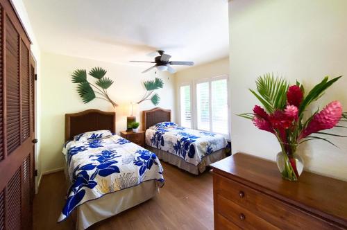 a bedroom with two beds and a vase with flowers at Manualoha 901 Minutes to Poipu in Koloa