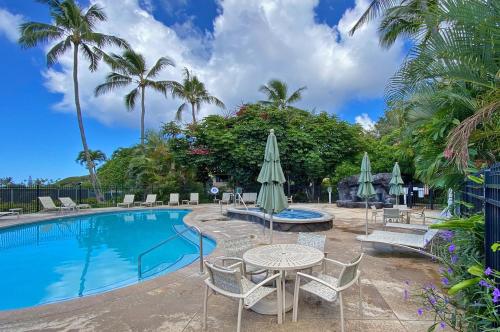 a pool with chairs and tables and umbrellas at Manualoha 901 Minutes to Poipu in Koloa