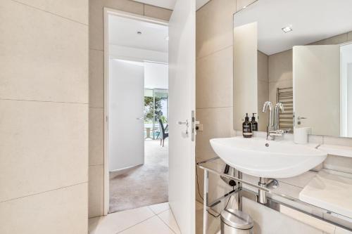 een badkamer met een wastafel en een spiegel bij Sentinel Beach House - Auckland Holiday Retreat in Auckland