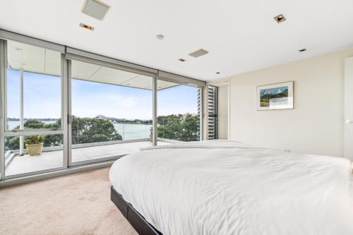 een slaapkamer met een groot bed en een groot raam bij Sentinel Beach House - Auckland Holiday Retreat in Auckland