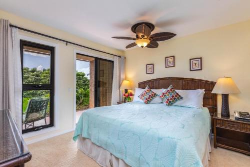 una camera da letto con un letto con un ventilatore a soffitto e una finestra di Nihi Kai 802 - Ocean Views a Kipu