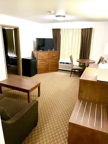 a hotel room with a desk and a couch and a table at Super 8 by Wyndham Hinton in Hinton