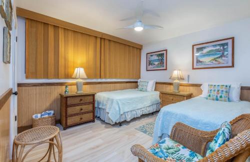 a hotel room with two beds and a chair at Poipu Shores 207A in Koloa