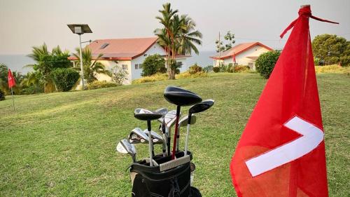 un gruppo di golf club seduti accanto a una bandiera rossa di Villa Ebouye a Kribi