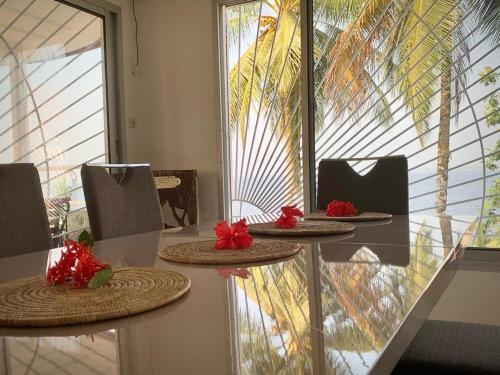 einen Tisch mit drei Platten drauf mit roten Blumen. in der Unterkunft Villa Ebouye in Kribi