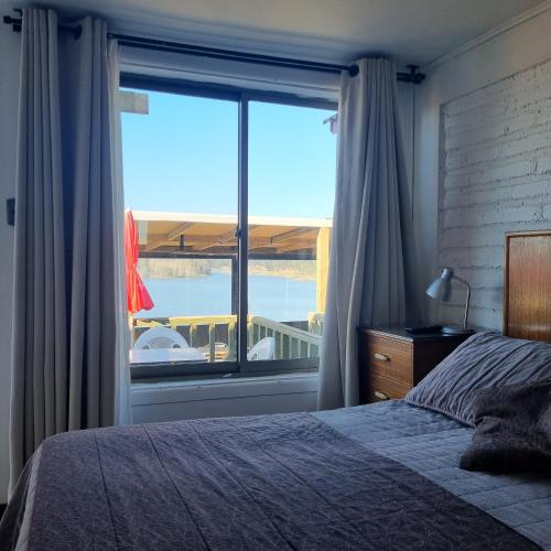 Dormitorio con ventana grande con vistas al agua en Max & Mar Pichilemu, en Pichilemu