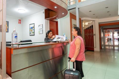 two women standing at a counter in an airport at Hotel Residencial C´BASTIAN in Tacna