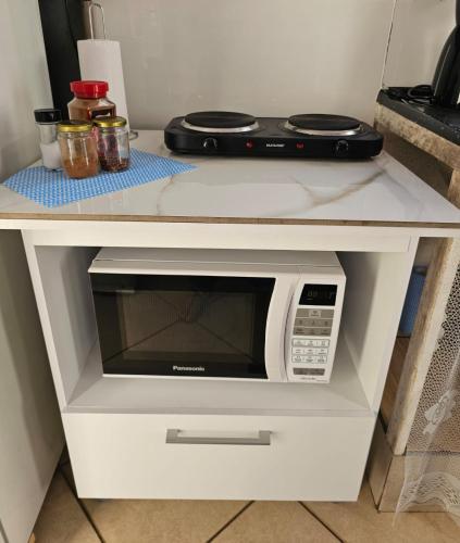 a microwave in a white cabinet with a stove at Apartamento Kit em Osasco Acesso Rodoanel Castelo Branco in Osasco
