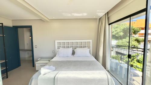 - une chambre avec un grand lit et un balcon dans l'établissement Ariana Apart Hotel Canasvieiras, à Florianópolis