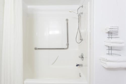 a white bathroom with a shower and towels at Super 8 by Wyndham Hinton in Hinton