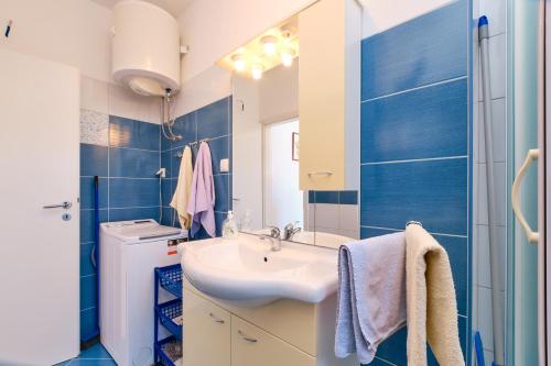 ein blau-weißes Bad mit einem Waschbecken und einem Spiegel in der Unterkunft Dina in Mali Lošinj
