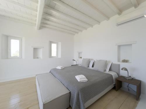 a white bedroom with a large bed and a wooden floor at Villa Prive 88 Mykonos in Fanari